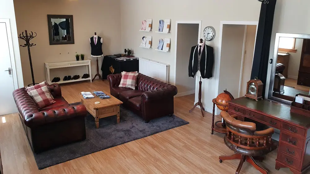Fitting room with oxblood leather chesterfield sofas, a mannequin in a waistcoat and shirt samples on the wall